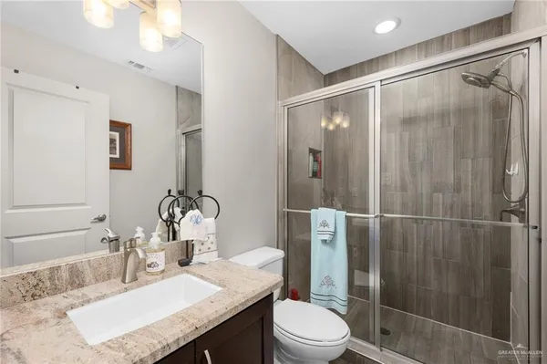 a bathroom with a granite countertop sink toilet and shower