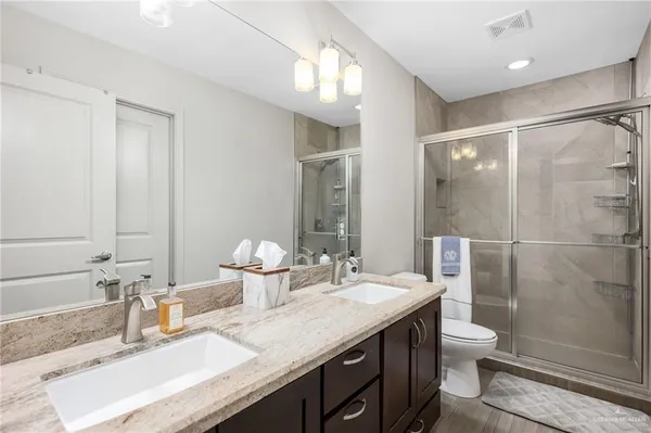 a bathroom with a double vanity sink toilet and shower