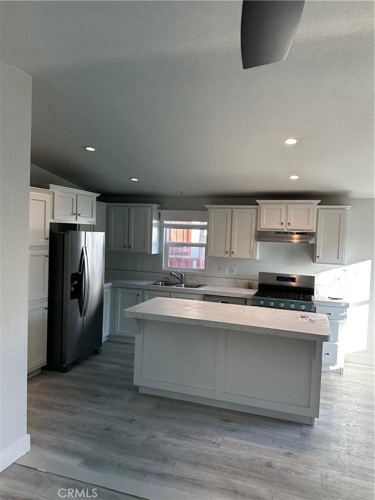 21845 Grand Terrace Road, Unit 12 Grand Terrace, CA 92313 - Photo 6 of 7 a large kitchen with stainless steel appliances a large counter top a stove and a refrigerator