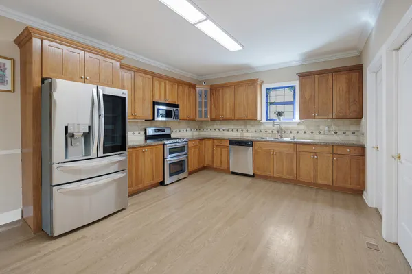 a kitchen with stainless steel appliances granite countertop a stove top oven a refrigerator a sink and dishwasher with wooden floor