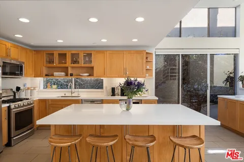 a kitchen with kitchen island a stove a sink a dining table and chairs