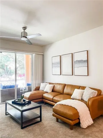 a living room with furniture ceiling fan and a large window