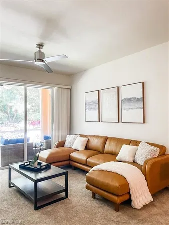 a living room with furniture ceiling fan and a large window