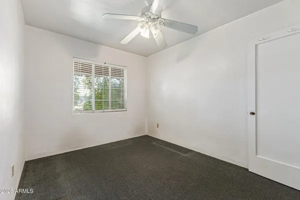 an empty room with a window and a fan