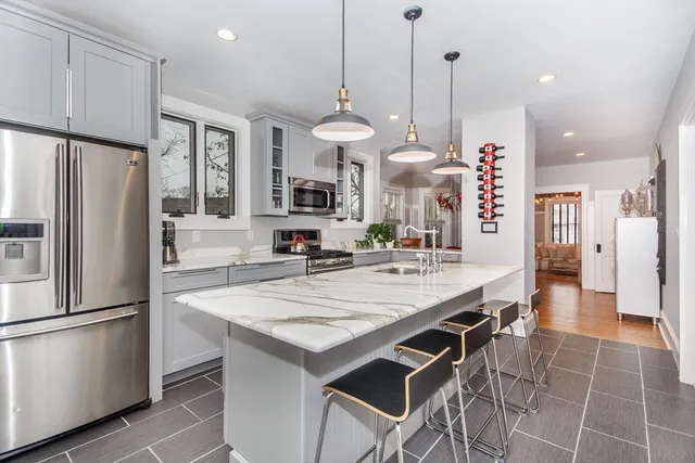 a kitchen with stainless steel appliances granite countertop a refrigerator a sink dishwasher a stove a dining table and chairs with wooden floor