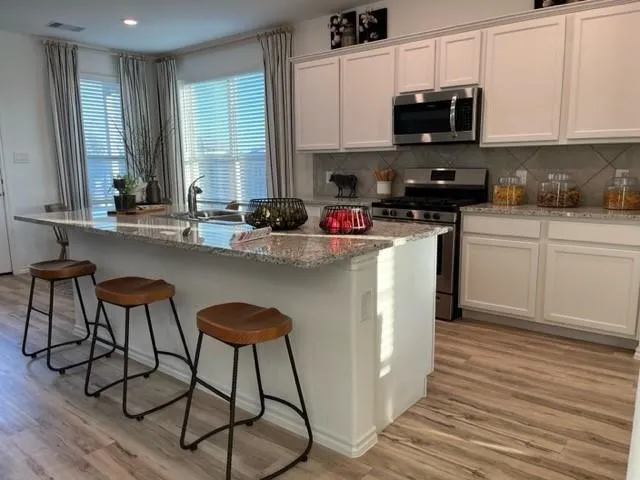a kitchen with stainless steel appliances a sink a stove a microwave and cabinets
