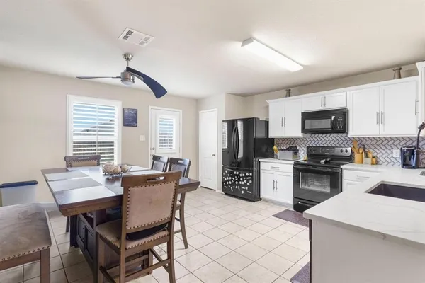 a kitchen with stainless steel appliances granite countertop a stove a refrigerator a sink a dining table and chairs