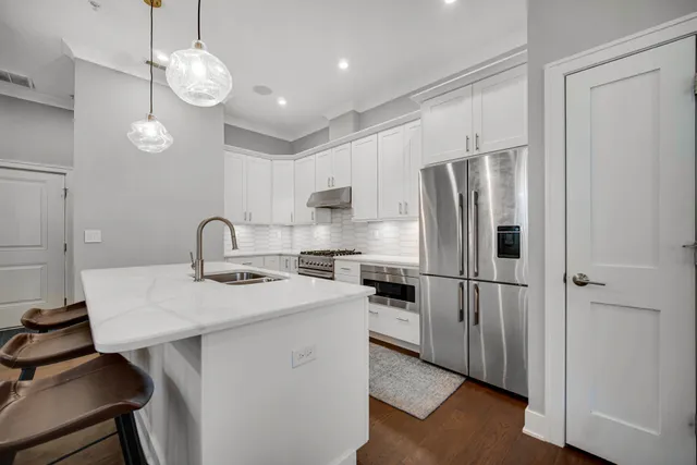 a kitchen with stainless steel appliances a table chairs refrigerator and cabinets