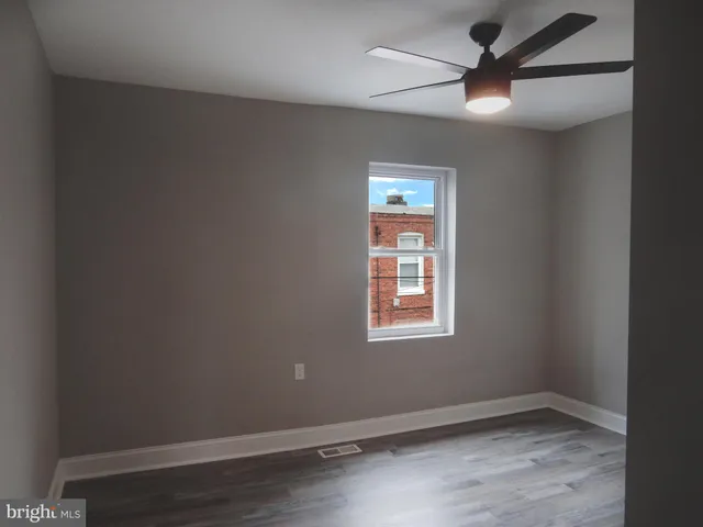 an empty room with a window and a fan
