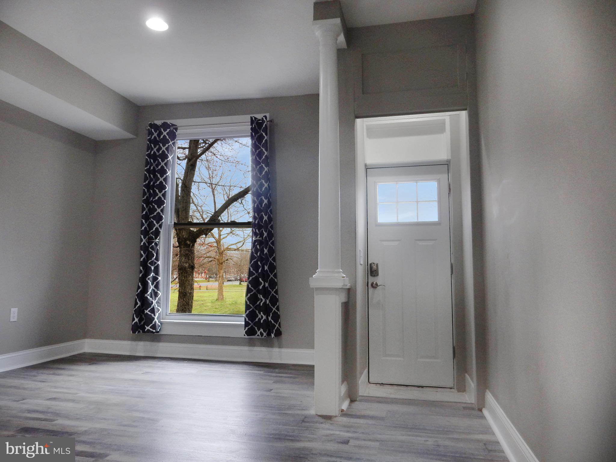 1111 Bayard Street Baltimore, MD 21223 - Photo 7 of 39 an empty room with wooden floor cabinet and windows