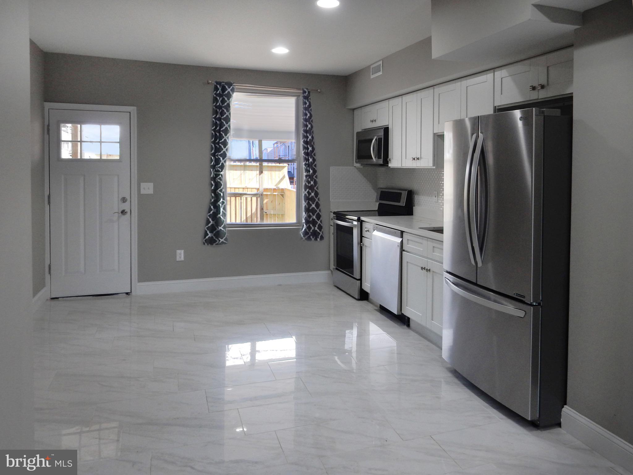 1111 Bayard Street Baltimore, MD 21223 - Photo 9 of 39 a kitchen with stainless steel appliances white cabinets and a refrigerator
