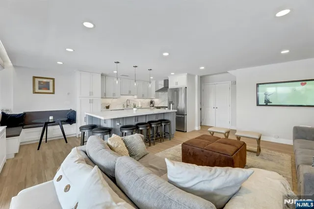 a kitchen with stainless steel appliances granite countertop a sink a stove a refrigerator cabinets and chairs