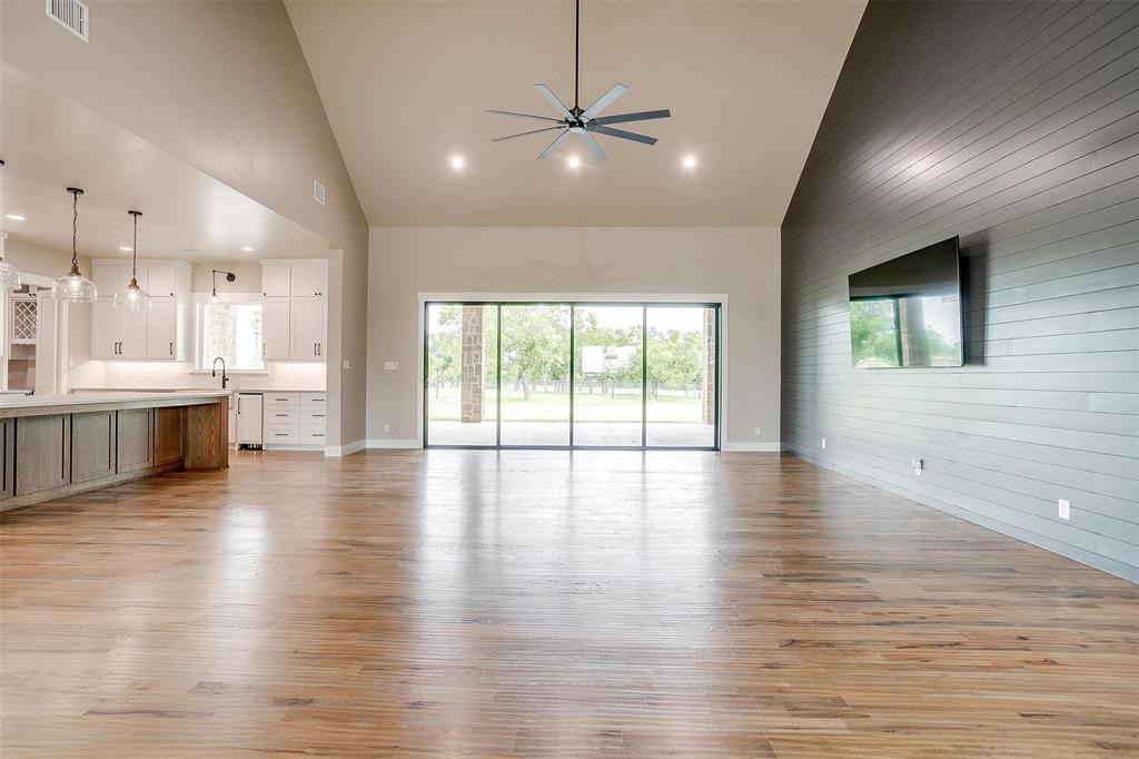 3019 Orchard Road Bowie, TX 76230 - Photo 11 of 40 a view of an empty room with wooden floor and a kitchen