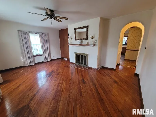 a view of empty room with wooden floor and fireplace