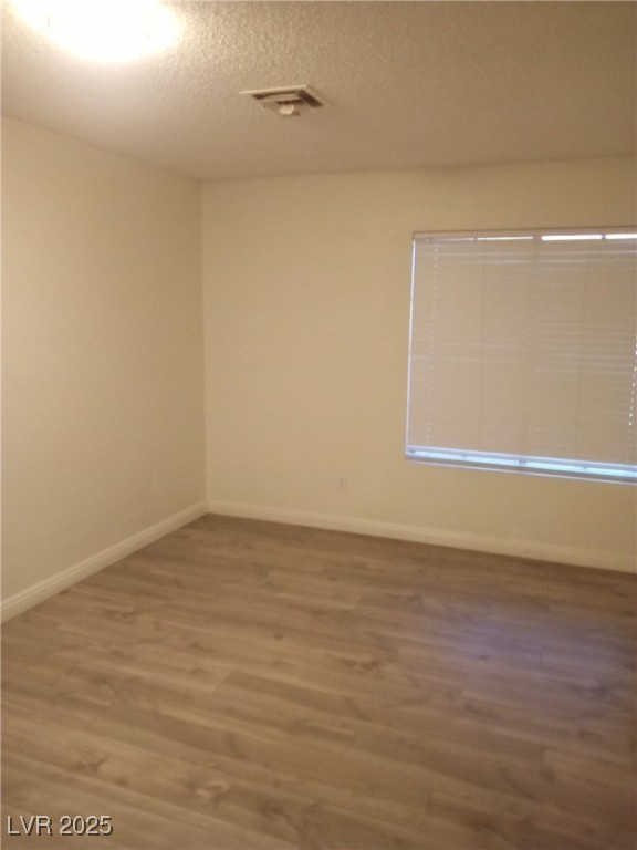 4830 Nara Vista Way, Unit 103 Las Vegas, NV 89103 - Photo 8 of 20 Spare room featuring a textured ceiling and wood finished floors
