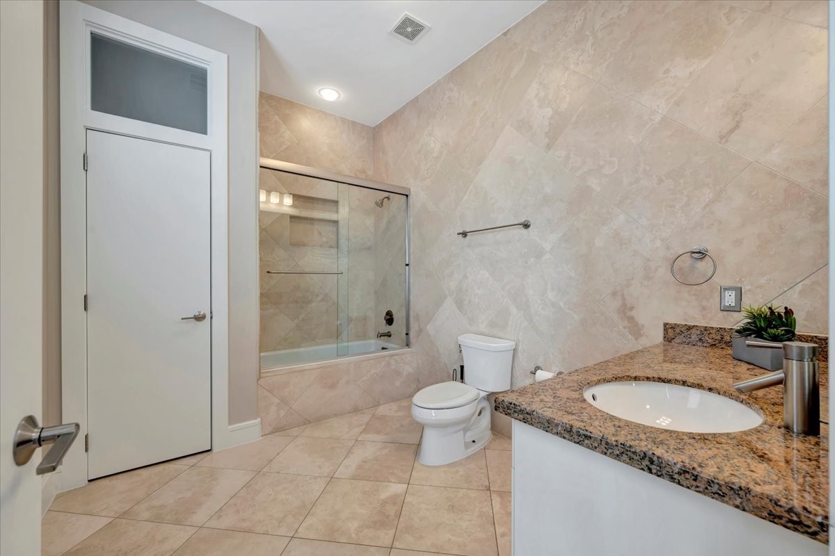 1202 Todville Road Seabrook, TX 77586 - Photo 20 of 45 A luxurious bathroom featuring travertine tiles on both the floors and walls, beautifully surrounding a sleek tub and shower combo for a cohesive and spa-like design.