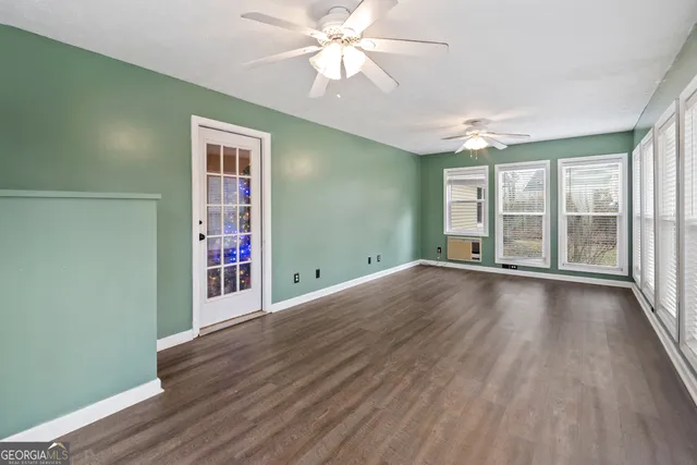a view of an empty room with window and wooden floor