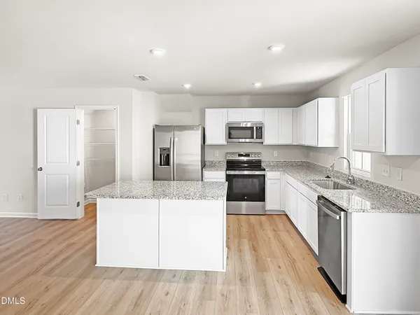 a large kitchen with stainless steel appliances granite countertop a stove a sink dishwasher and a refrigerator with wooden floor