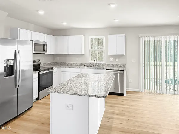a kitchen with stainless steel appliances granite countertop a stove a sink dishwasher a refrigerator and white cabinets with wooden floor