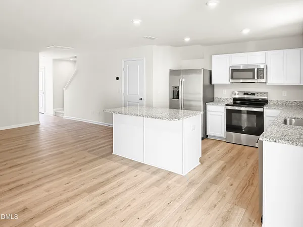 a large kitchen with stainless steel appliances granite countertop a stove a sink dishwasher and a refrigerator with wooden floor
