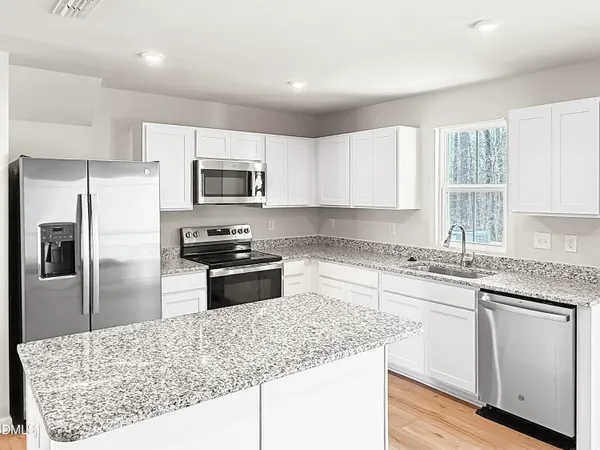 a kitchen with granite countertop white cabinets and stainless steel appliances