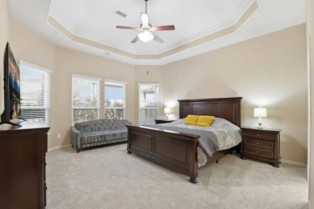a spacious bedroom with a bed a couch and a chandelier