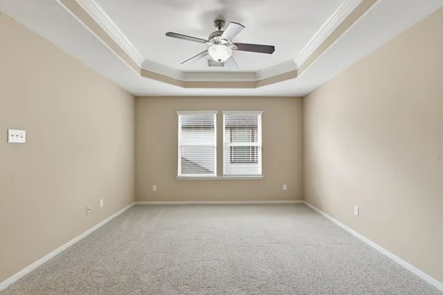 an empty room with a chandelier fan and windows