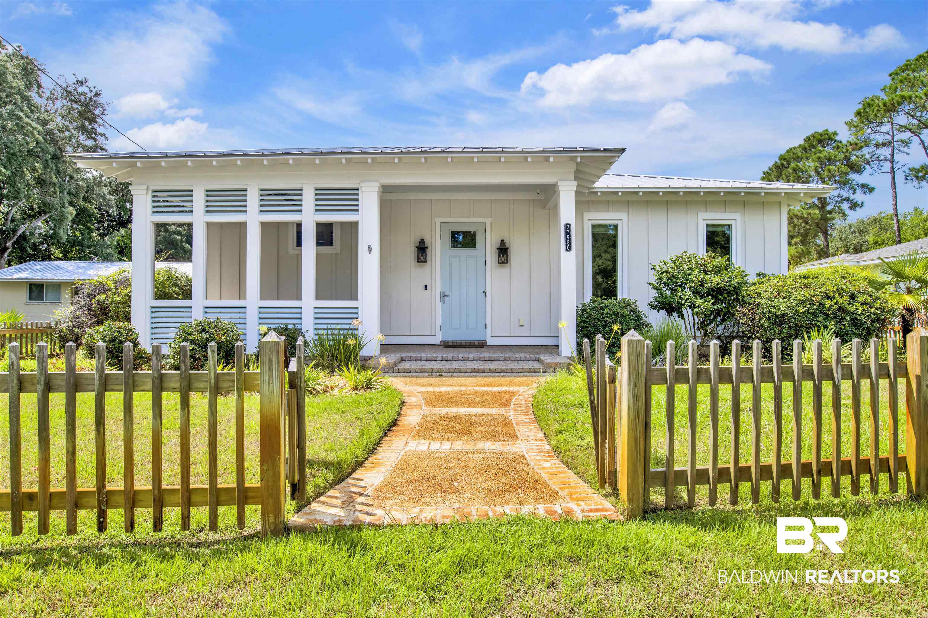 27980 Canal Road Orange Beach, AL 36561 - Photo 2 of 46 View of front of home with board and batten siding, a fenced front yard, a metal roof, and covered porch