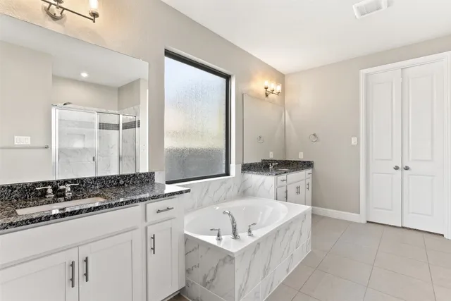 a bathroom with a granite countertop tub sink and mirror