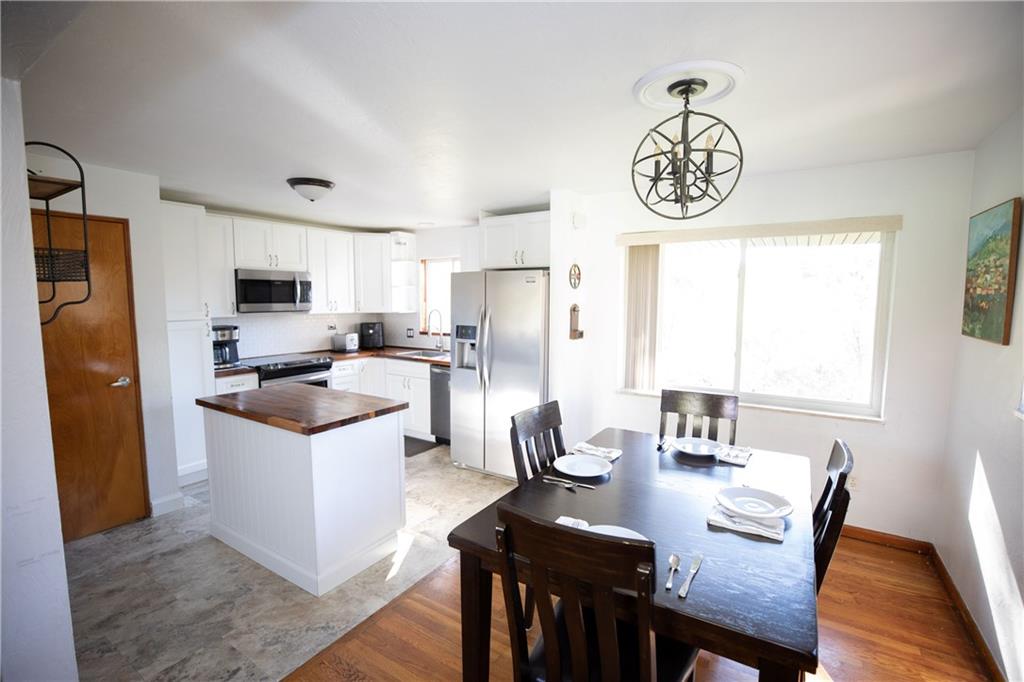 133 Church Road Pittsburgh, PA 15209 - Photo 7 of 20 a kitchen with a refrigerator a stove a sink and a dining table with wooden floor