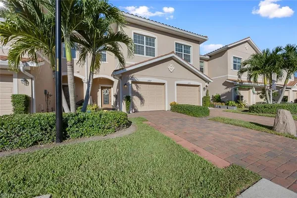 a front view of a house with a garden and trees