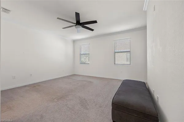 an empty room with a ceiling fan and windows
