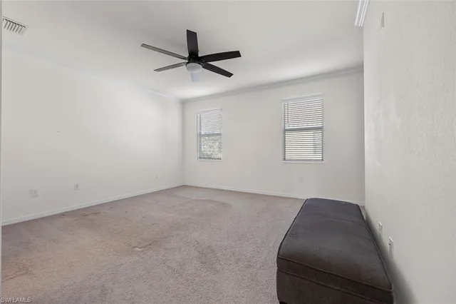 an empty room with a ceiling fan and windows