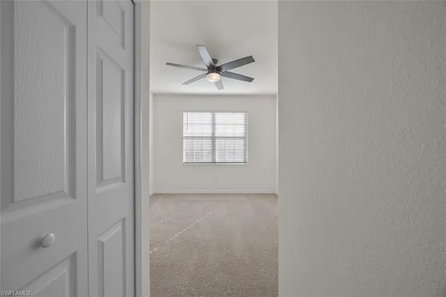 an empty room with windows and fan