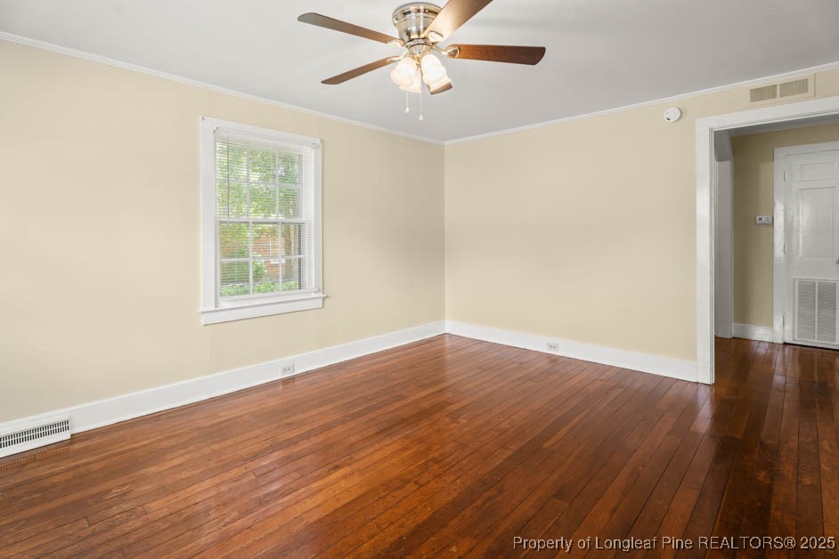 1007 Jenkins Street Lumberton, NC 28358 - Photo 5 of 44 an empty room with wooden floor chandelier fan and windows