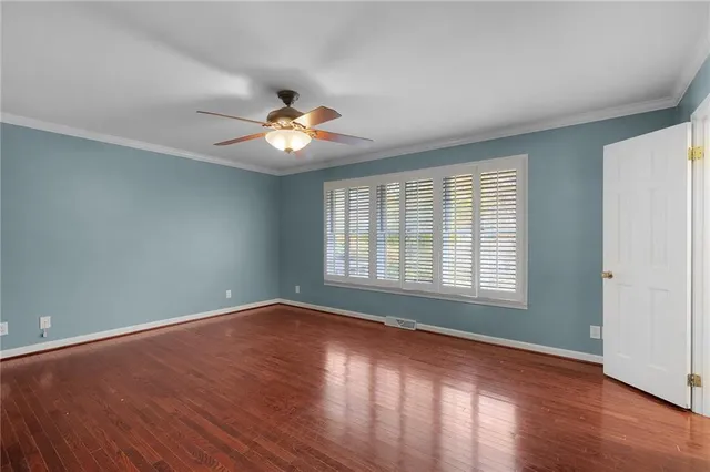 a view of an empty room with window and wooden floor