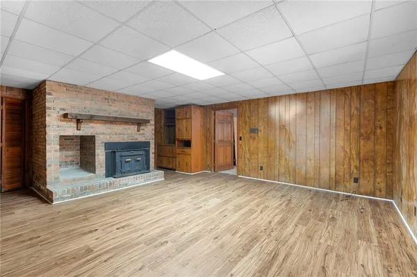 an empty room with wooden floor fireplace and windows