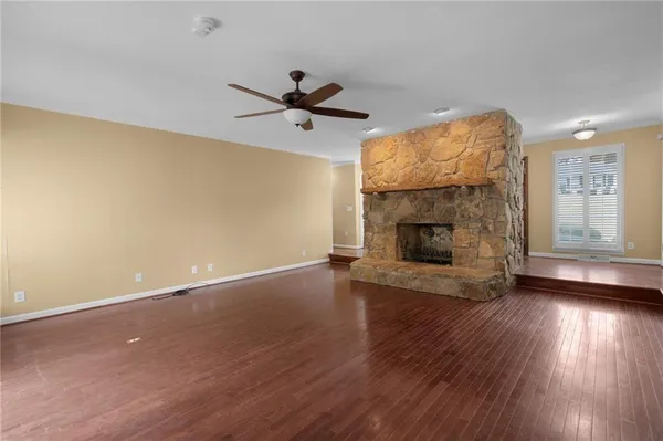 an empty room with wooden floor a fireplace and windows