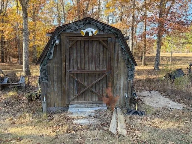 a view of a wooden house with a small yard and large tree