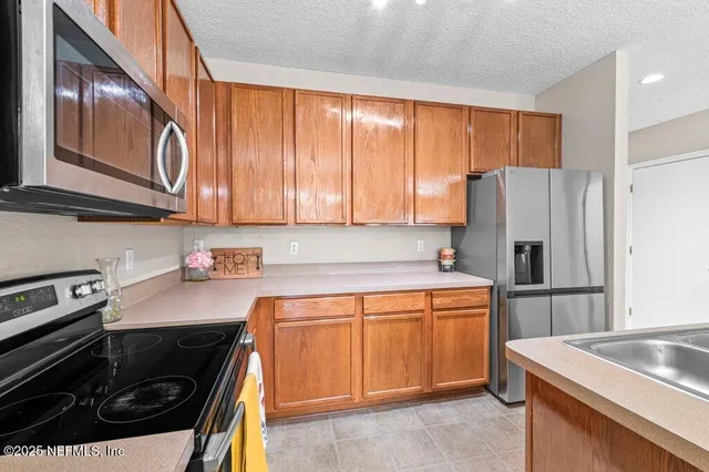 a large white kitchen with kitchen island a sink dishwasher a refrigerator and a fireplace with wooden floor