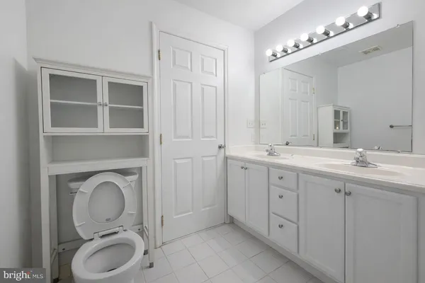 a en suite bathroom with a granite countertop double vanity sink a mirror and a toilet