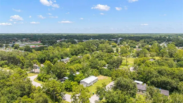 an aerial view of residential houses with outdoor space and trees