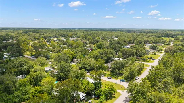 an aerial view of residential houses with outdoor space and trees