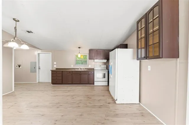 a large white kitchen with a refrigerator a microwave and a sink