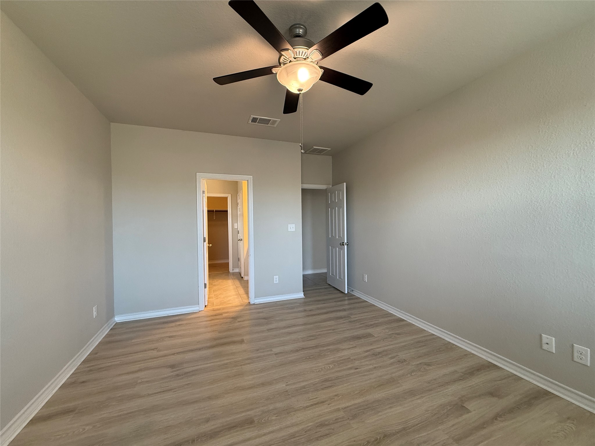 5989 Malta Circle Round Rock, TX 78665 - Photo 19 of 36 Unfurnished bedroom with a walk in closet, light wood-style floors, and ceiling fan