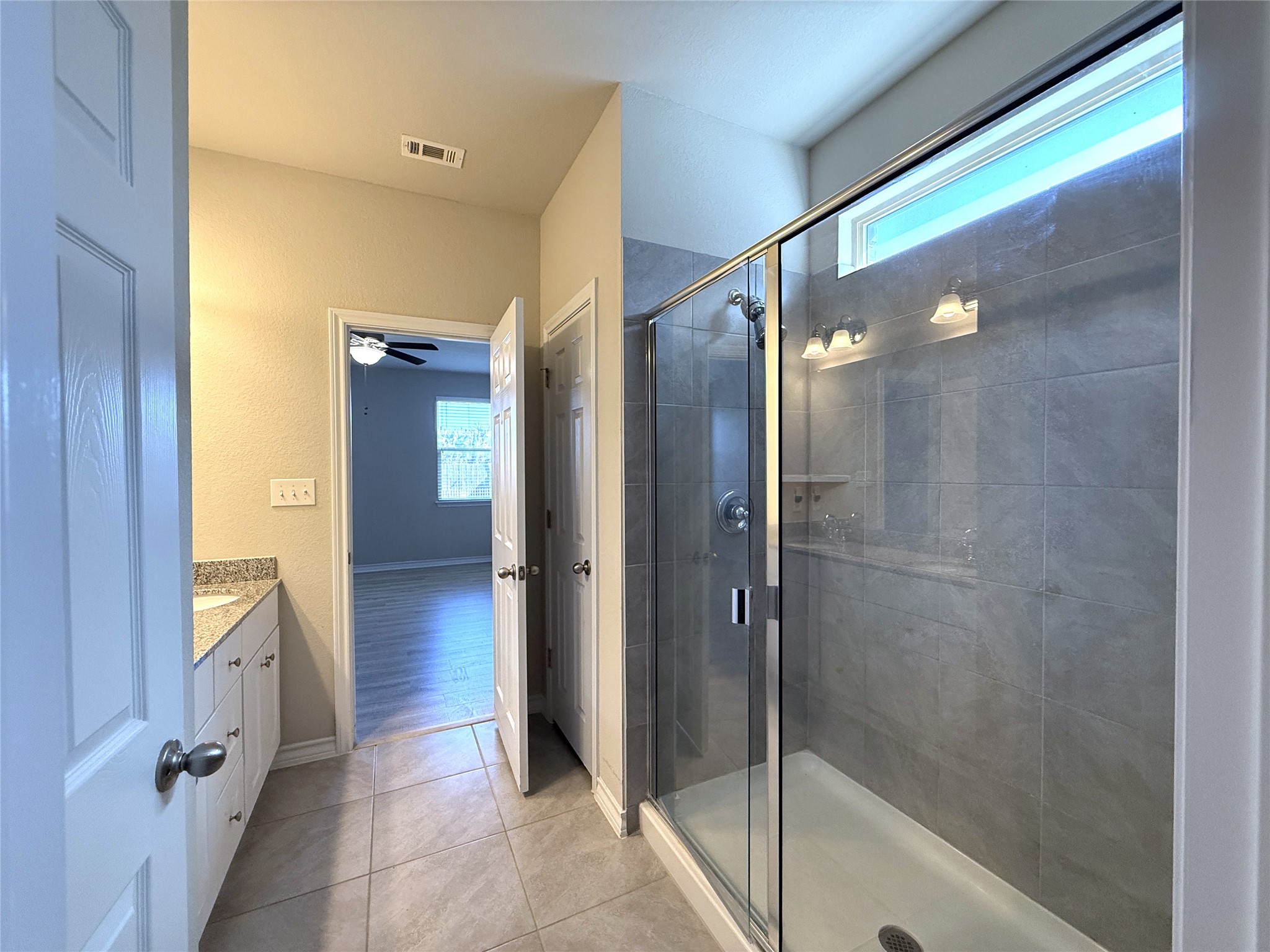 5989 Malta Circle Round Rock, TX 78665 - Photo 23 of 36 Full bathroom with plenty of natural light, a stall shower, vanity, and light tile patterned floors