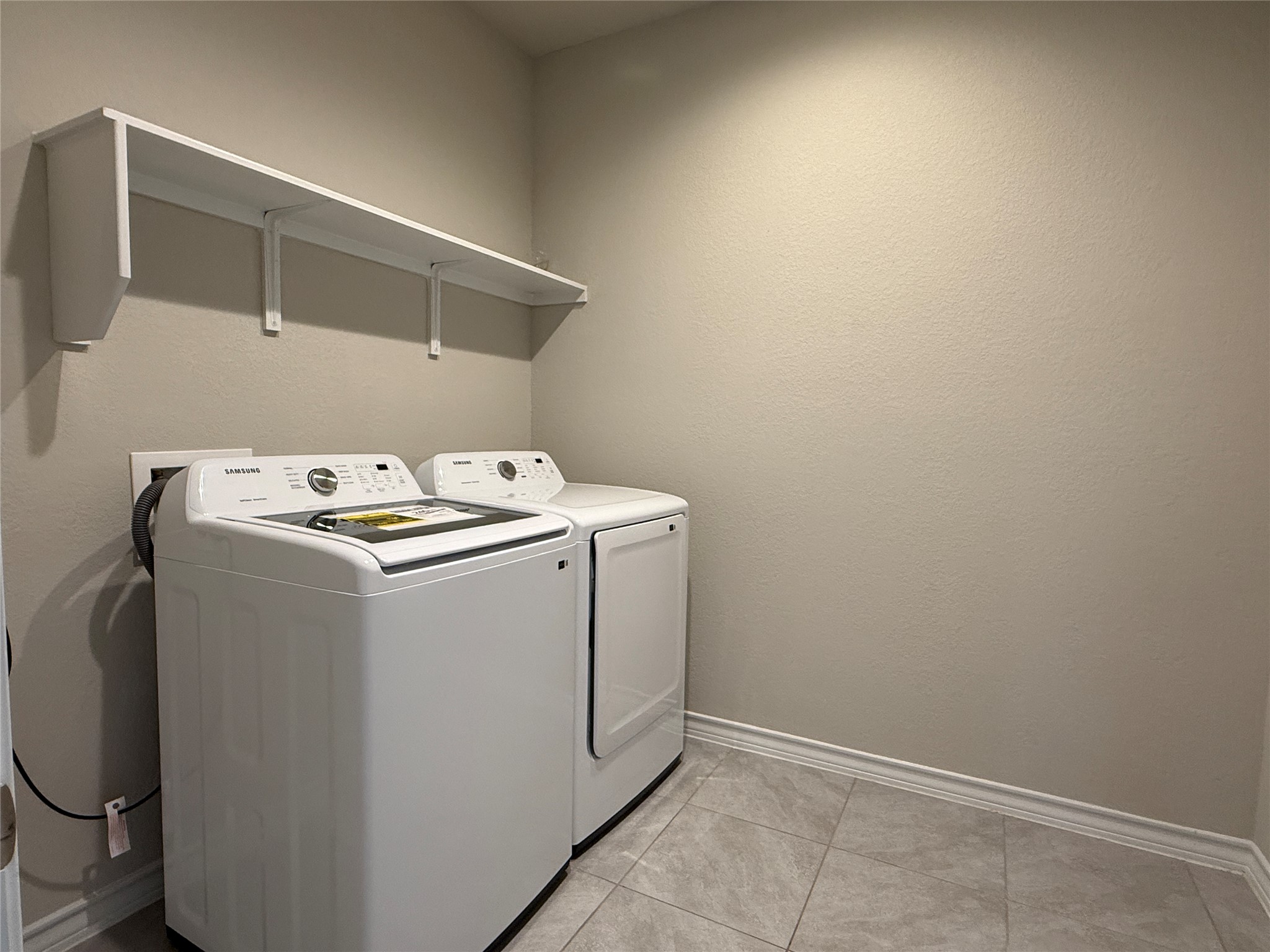 5989 Malta Circle Round Rock, TX 78665 - Photo 33 of 36 Laundry room with washing machine and clothes dryer and light tile patterned floors