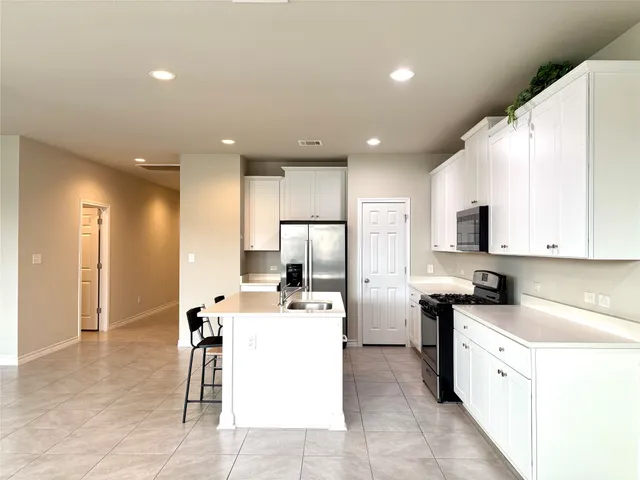 a kitchen with a refrigerator a stove top oven and a dining table with a living room view