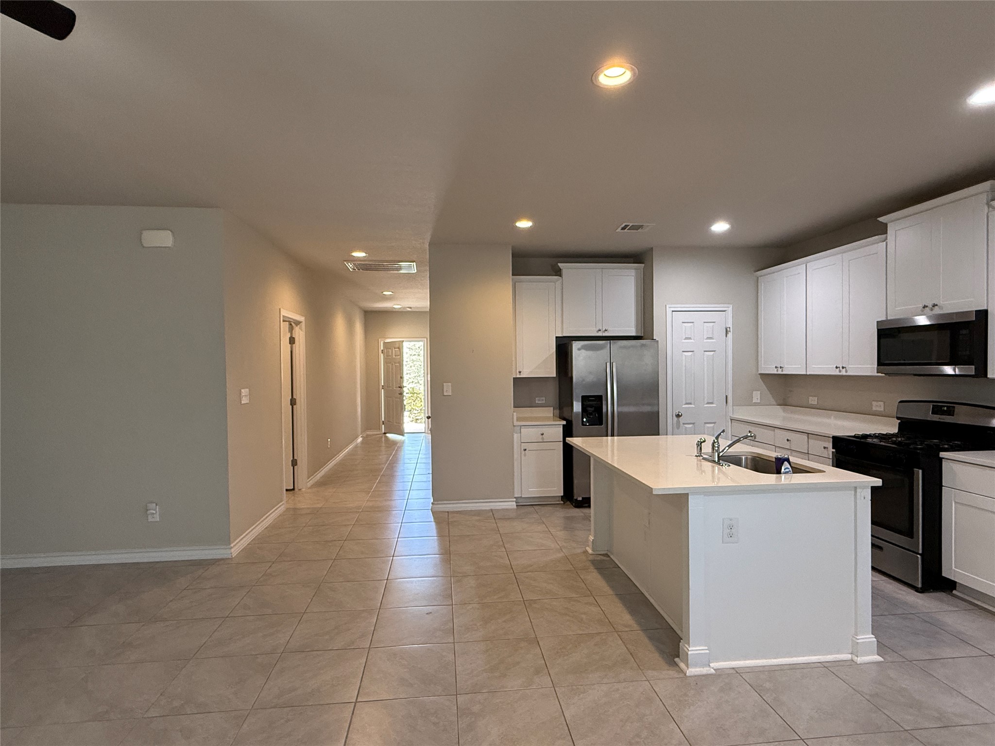 5989 Malta Circle Round Rock, TX 78665 - Photo 5 of 36 Kitchen featuring stainless steel appliances, white cabinets, a center island with sink, recessed lighting, and light tile patterned floors