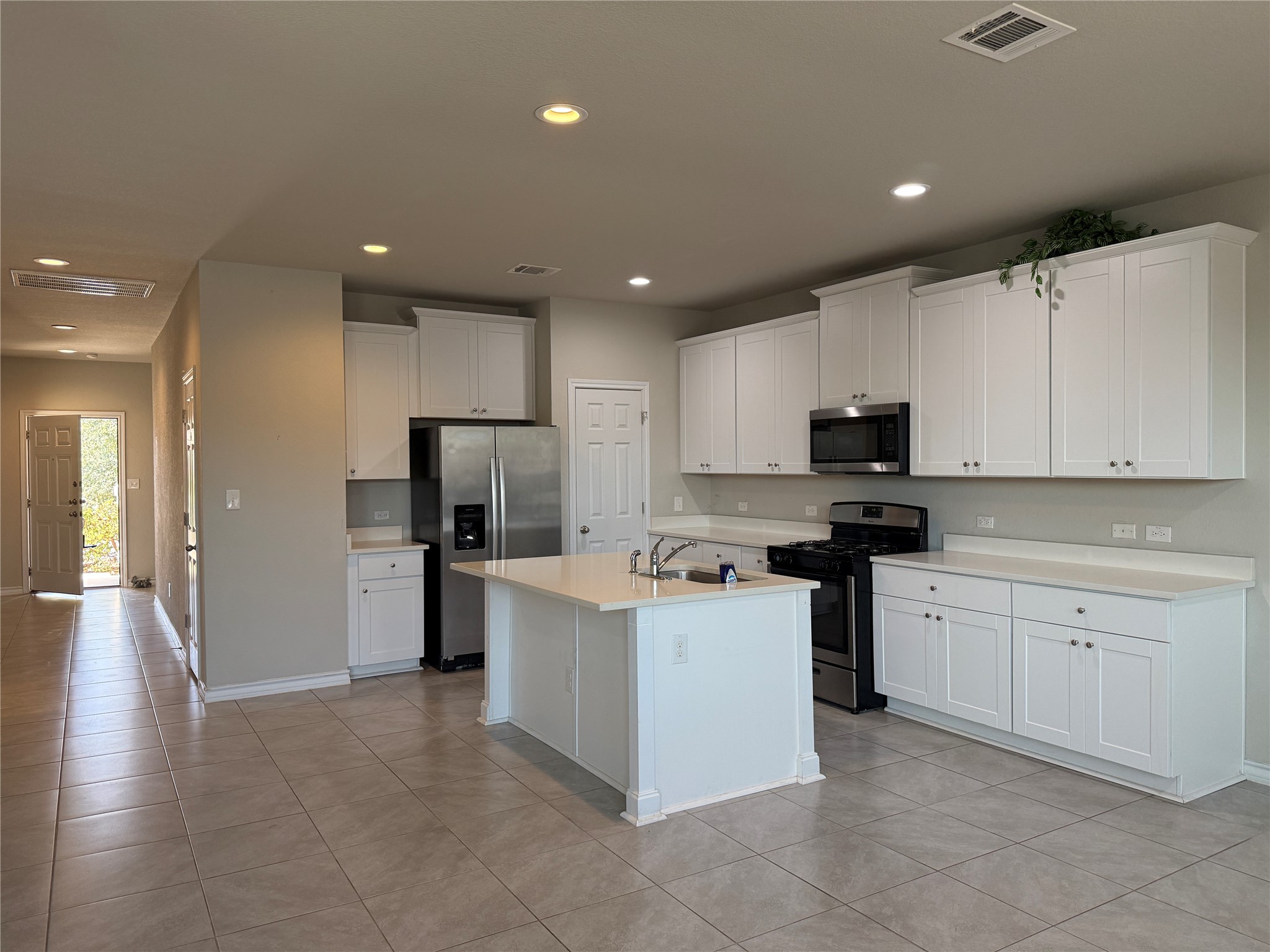 5989 Malta Circle Round Rock, TX 78665 - Photo 6 of 36 Kitchen with stainless steel appliances, white cabinets, recessed lighting, an island with sink, and light tile patterned floors